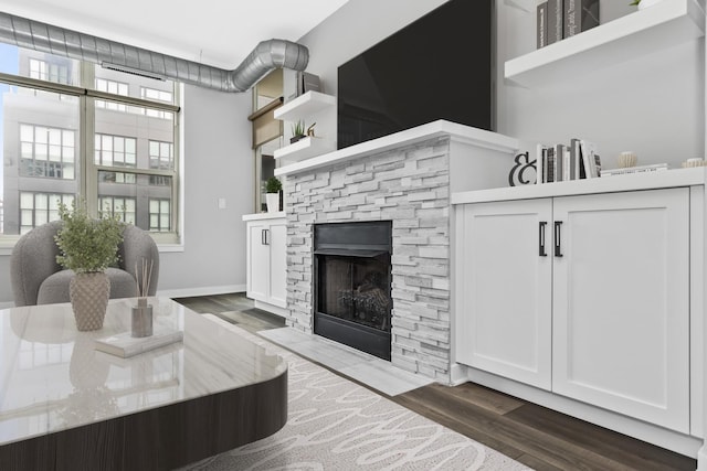 living room featuring dark wood-type flooring and a stone fireplace