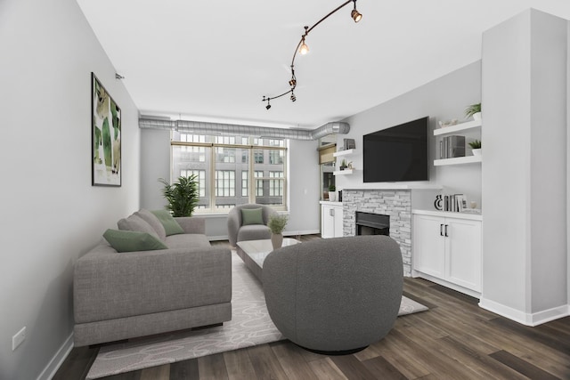 living room with a fireplace, dark hardwood / wood-style floors, and track lighting