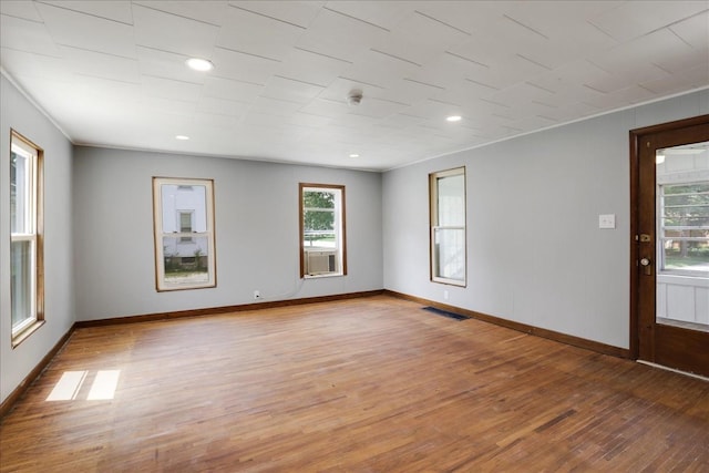 empty room featuring hardwood / wood-style floors, cooling unit, and ornamental molding