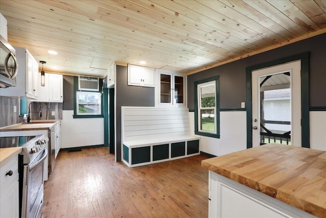 kitchen with appliances with stainless steel finishes, wood ceiling, sink, butcher block countertops, and white cabinetry