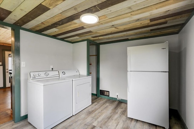 clothes washing area with independent washer and dryer, light hardwood / wood-style flooring, and wood ceiling