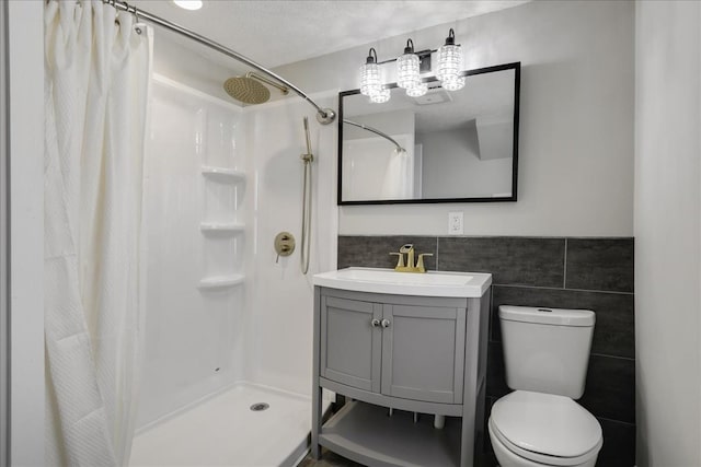 bathroom with a shower with curtain, a textured ceiling, toilet, vanity, and tile walls