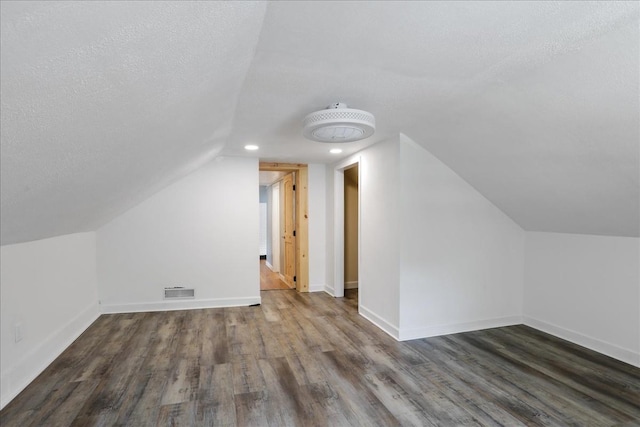 bonus room with dark hardwood / wood-style flooring, a textured ceiling, and vaulted ceiling