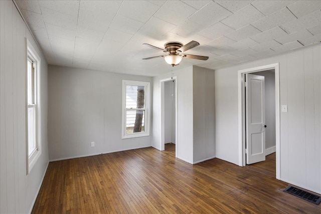 unfurnished room with a wealth of natural light, ceiling fan, and dark hardwood / wood-style floors