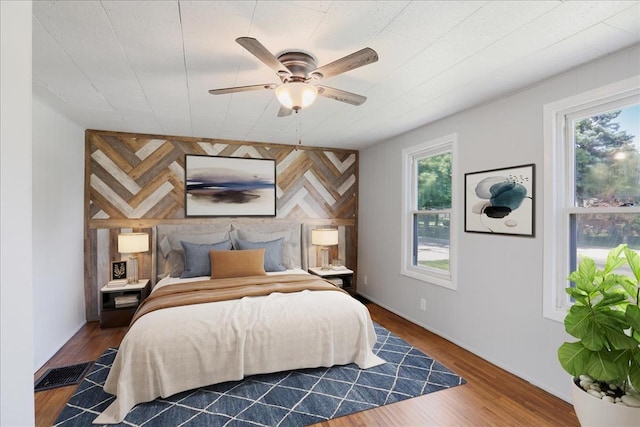 bedroom featuring multiple windows, ceiling fan, and dark hardwood / wood-style flooring