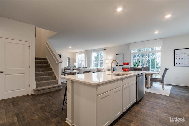 kitchen featuring dishwasher, dark wood-type flooring, sink, an island with sink, and white cabinetry