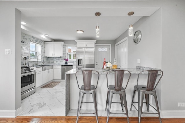 kitchen featuring light stone countertops, white cabinetry, sink, stainless steel appliances, and tasteful backsplash