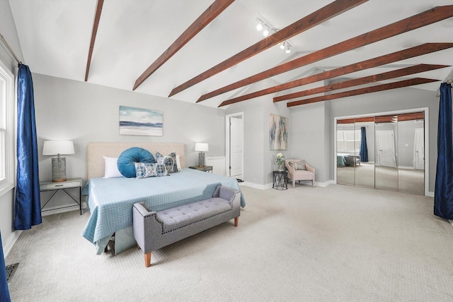 carpeted bedroom featuring beamed ceiling and rail lighting