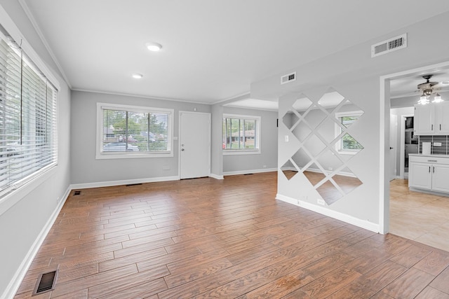 interior space featuring ceiling fan, ornamental molding, and light wood-type flooring