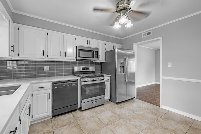 kitchen featuring ceiling fan, light tile patterned floors, ornamental molding, white cabinetry, and stainless steel appliances