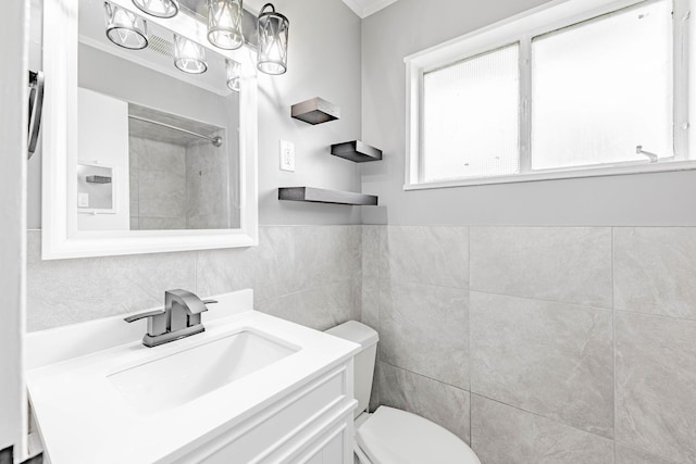 bathroom with a shower, vanity, toilet, and tile walls