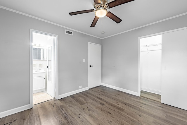 unfurnished bedroom with crown molding, ceiling fan, light wood-type flooring, connected bathroom, and a closet