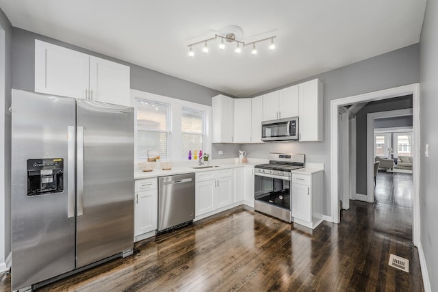 kitchen featuring dark hardwood / wood-style flooring, white cabinetry, sink, and appliances with stainless steel finishes