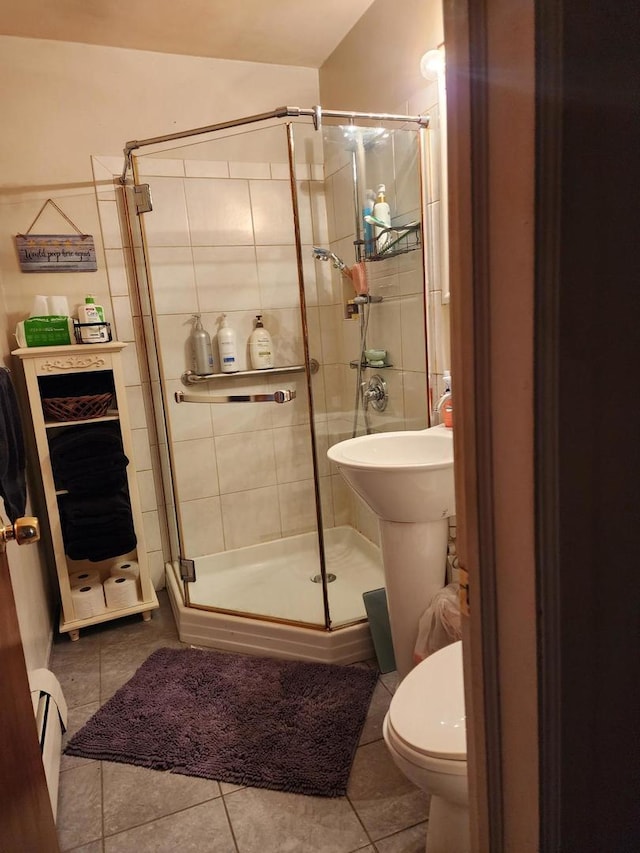 bathroom with tile patterned flooring, an enclosed shower, a baseboard radiator, and toilet