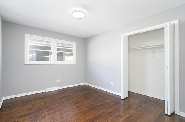 unfurnished bedroom featuring dark hardwood / wood-style floors and a closet