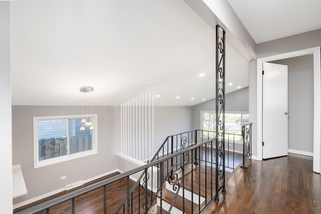 corridor with a healthy amount of sunlight, dark hardwood / wood-style flooring, and vaulted ceiling