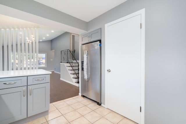 kitchen with stainless steel fridge, gray cabinets, light tile patterned floors, and hanging light fixtures