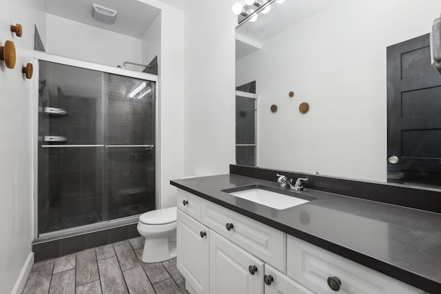 bathroom featuring vanity, walk in shower, and toilet