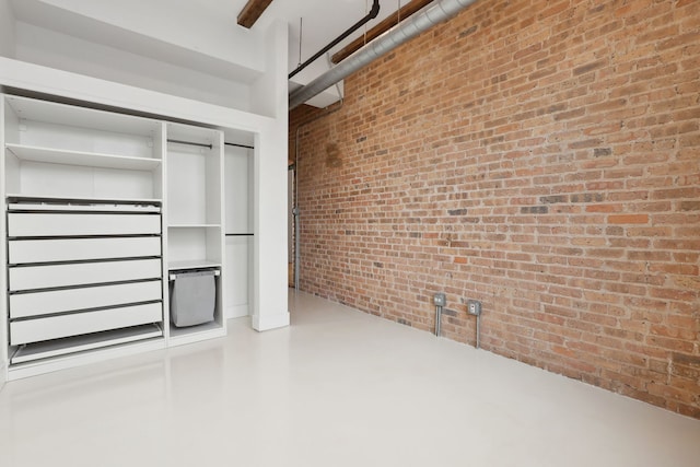 interior space featuring a closet, concrete floors, and brick wall