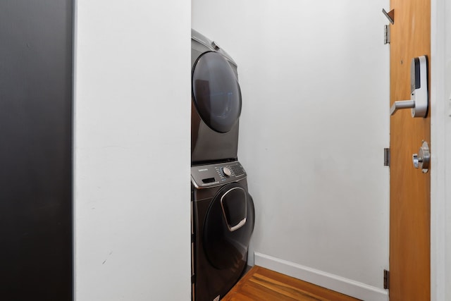 clothes washing area featuring stacked washer / drying machine and hardwood / wood-style floors