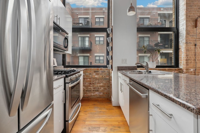 kitchen featuring decorative light fixtures, sink, white cabinets, dark stone counters, and stainless steel appliances