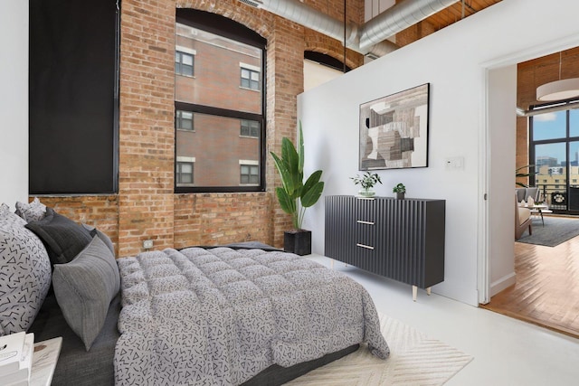 bedroom with a towering ceiling and brick wall