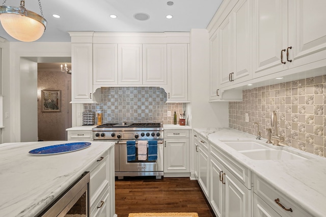 kitchen with double oven range, light stone countertops, white cabinetry, and pendant lighting