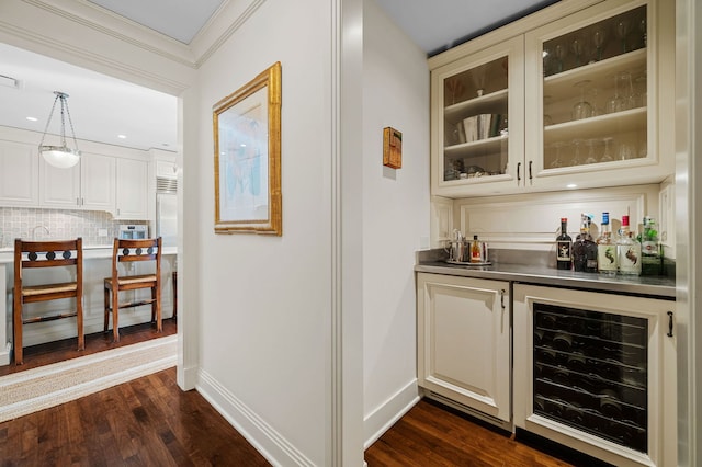 bar featuring tasteful backsplash, dark wood-type flooring, beverage cooler, hanging light fixtures, and ornamental molding