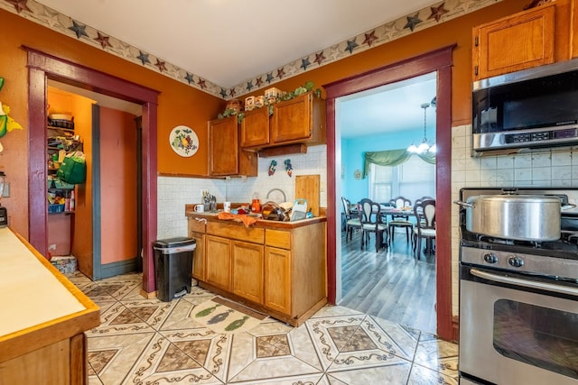 kitchen featuring an inviting chandelier, light wood-type flooring, and appliances with stainless steel finishes