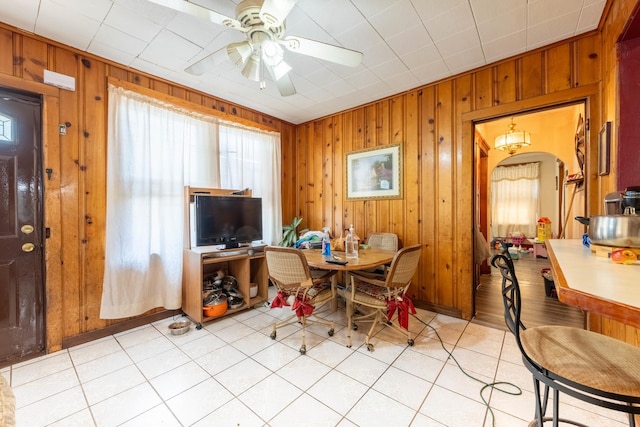 dining space with ceiling fan and wooden walls