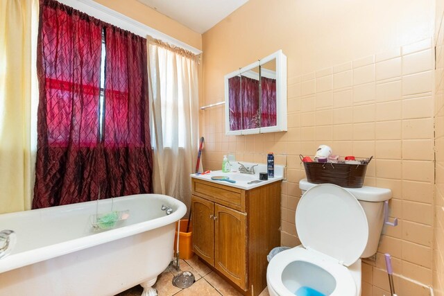 bathroom featuring toilet, a bathtub, tile walls, tile patterned floors, and vanity