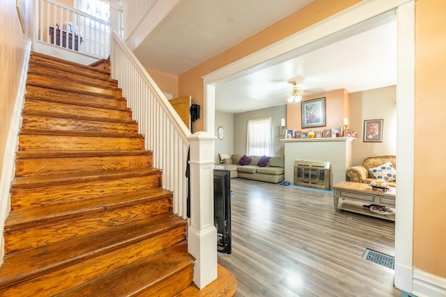 stairway featuring ceiling fan and hardwood / wood-style floors