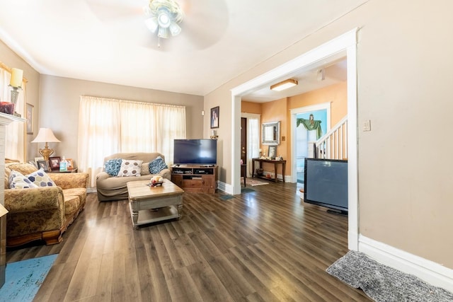 living room featuring dark wood-type flooring, ceiling fan, and a wealth of natural light