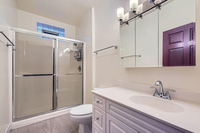 bathroom with wood-type flooring, vanity, toilet, and an enclosed shower