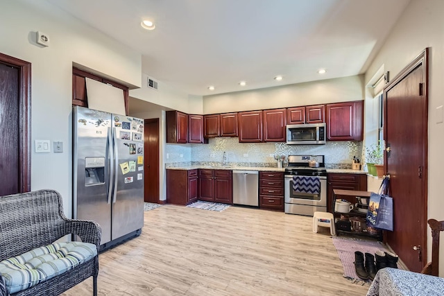 kitchen with light hardwood / wood-style floors, sink, stainless steel appliances, and tasteful backsplash