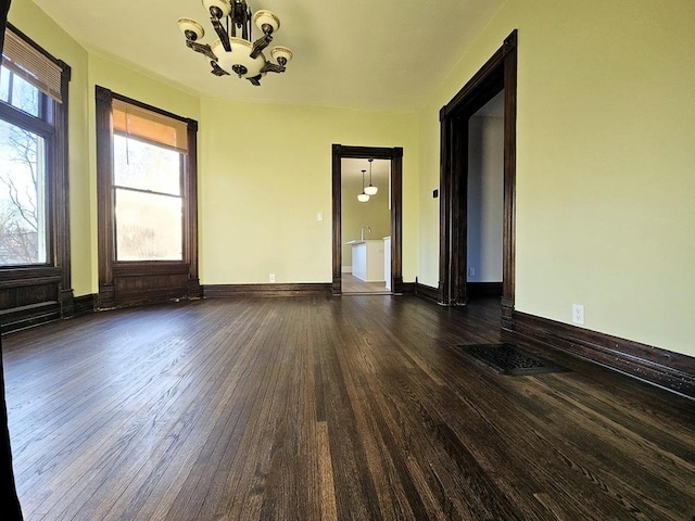 empty room with a chandelier and dark hardwood / wood-style floors