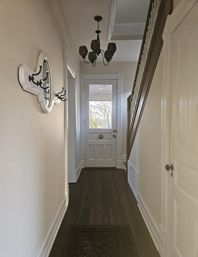doorway featuring ornamental molding, an inviting chandelier, visible vents, and dark wood finished floors