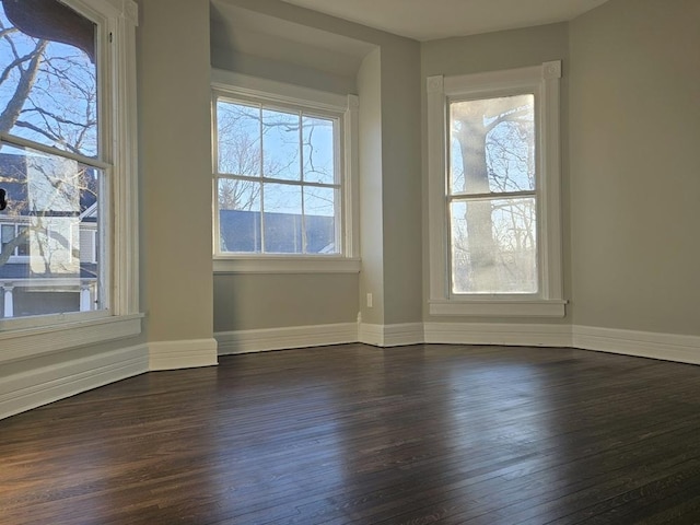 unfurnished room with dark wood-style floors and baseboards