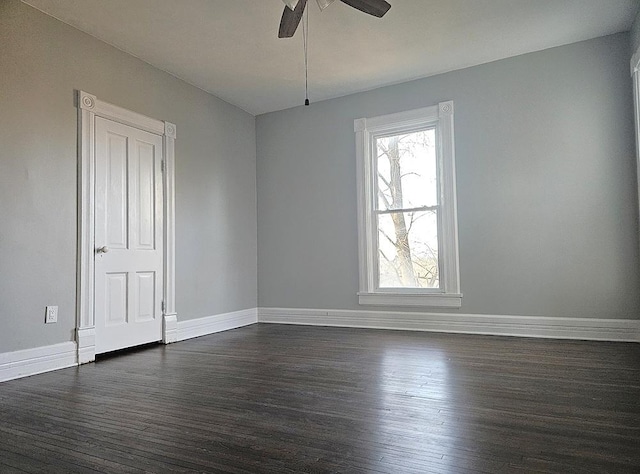 empty room featuring a ceiling fan, baseboards, and dark wood finished floors