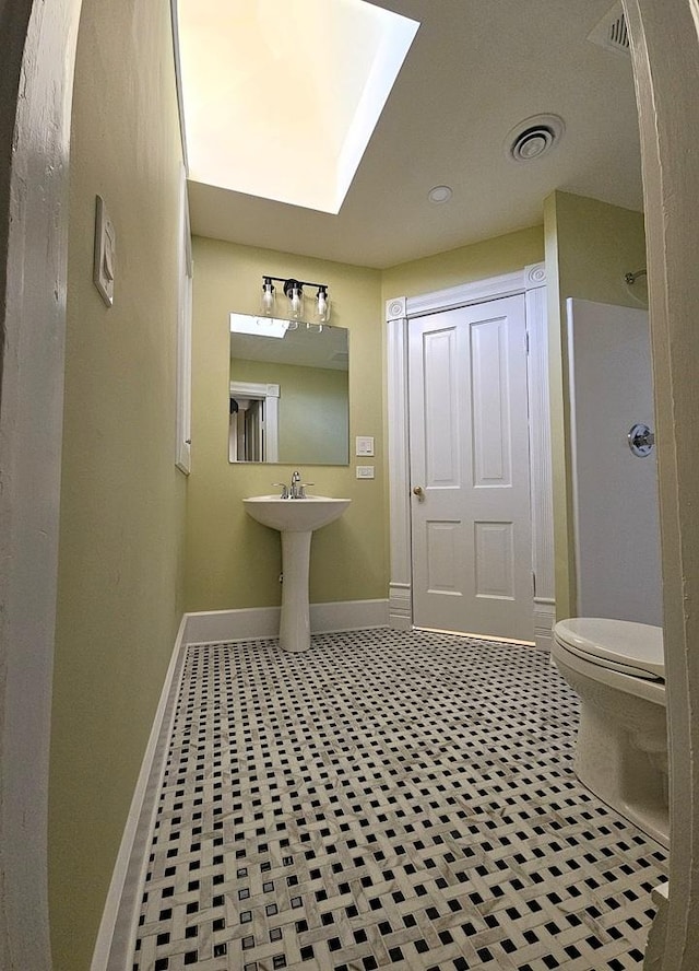 bathroom featuring baseboards, tile patterned flooring, toilet, visible vents, and a skylight