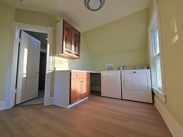 laundry area featuring washer and dryer, cabinets, and light wood-type flooring