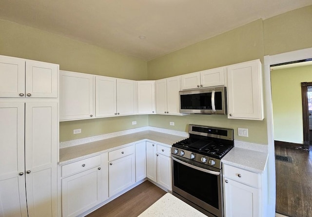 kitchen featuring dark wood-type flooring, stainless steel appliances, and white cabinets