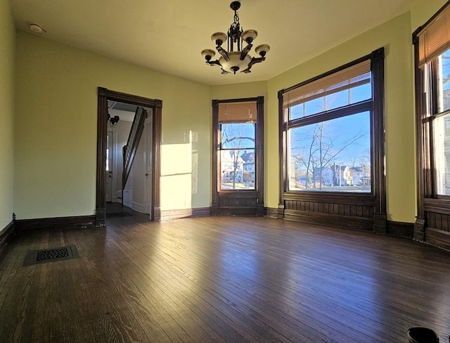 empty room with dark hardwood / wood-style floors and a notable chandelier