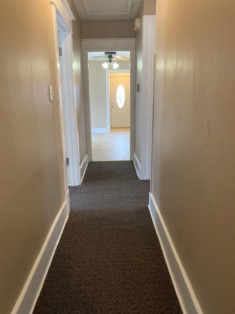 hallway featuring dark colored carpet