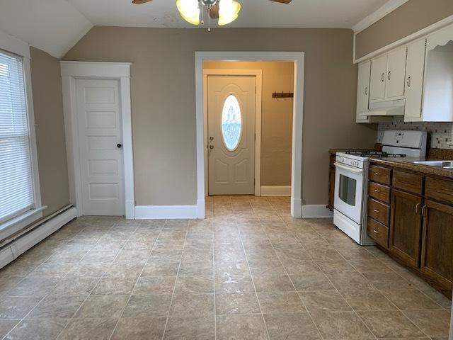 kitchen featuring tasteful backsplash, vaulted ceiling, a wealth of natural light, white cabinets, and white gas range oven