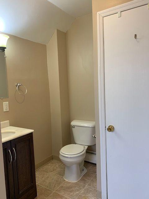 bathroom featuring a baseboard heating unit, toilet, and vanity