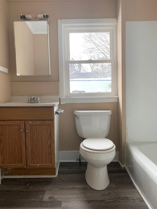 bathroom with hardwood / wood-style flooring, toilet, vanity, and a bathing tub