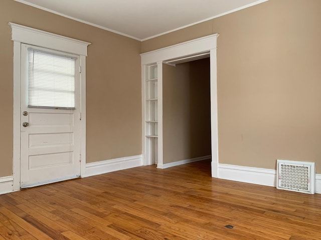 foyer with wood-type flooring and crown molding