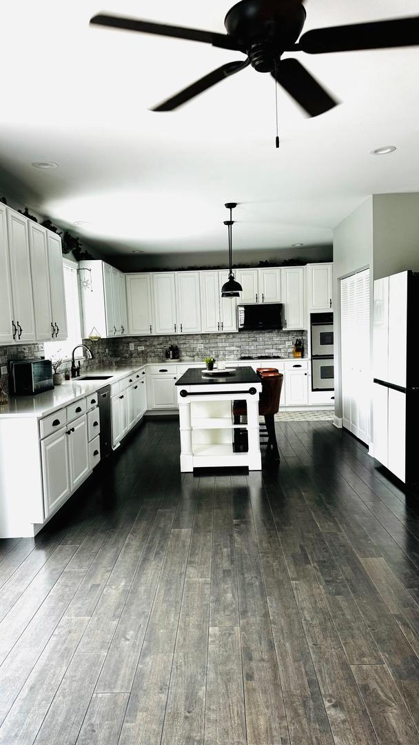 kitchen with dark hardwood / wood-style floors, decorative light fixtures, stainless steel double oven, white cabinets, and sink