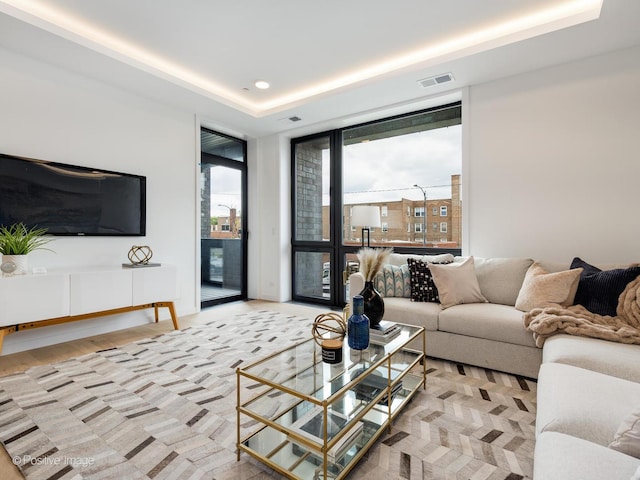 living room with a tray ceiling and light hardwood / wood-style flooring